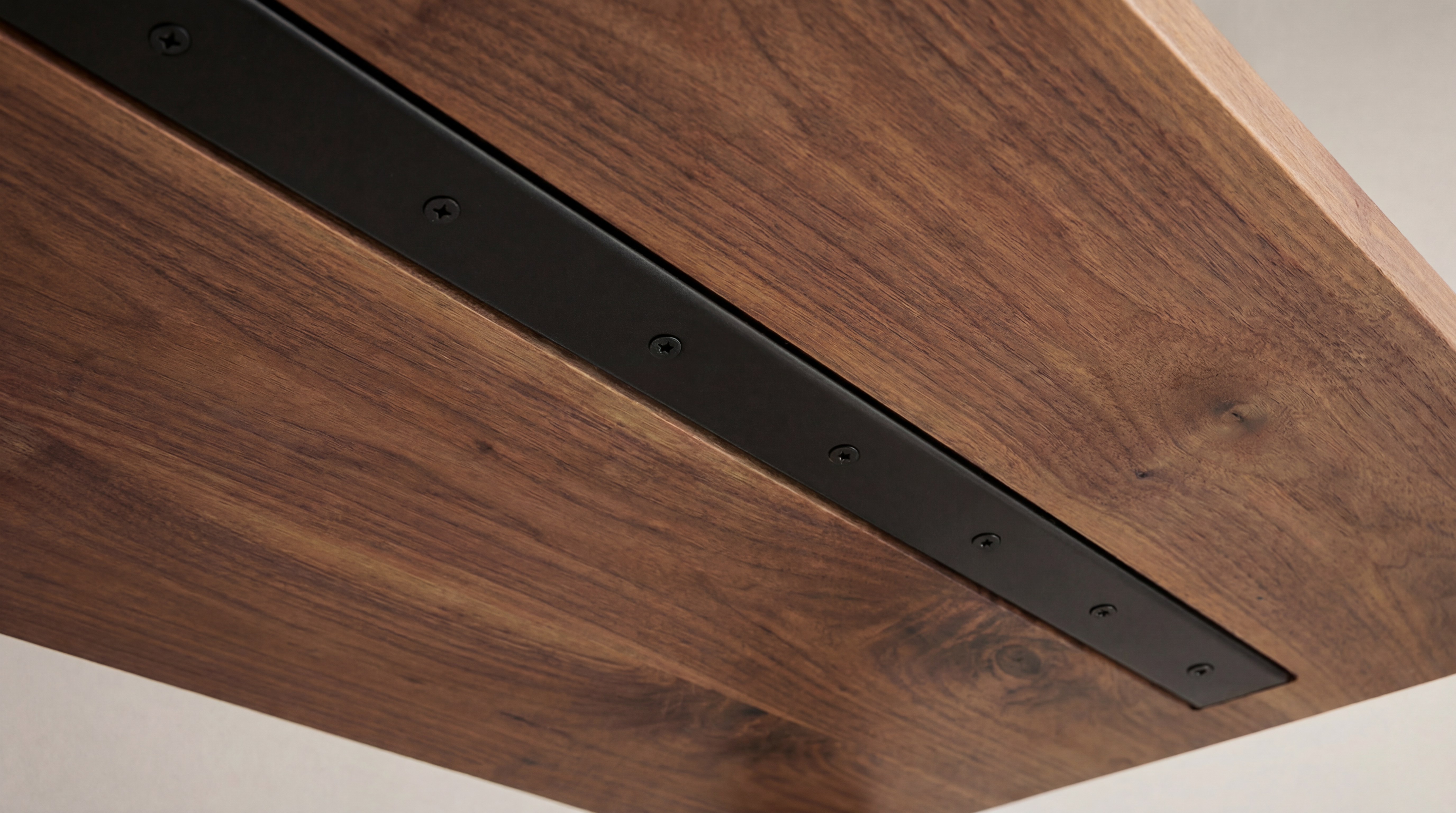 Underside of a wood countertop showing C-channel steel reinforcement routed in flush.