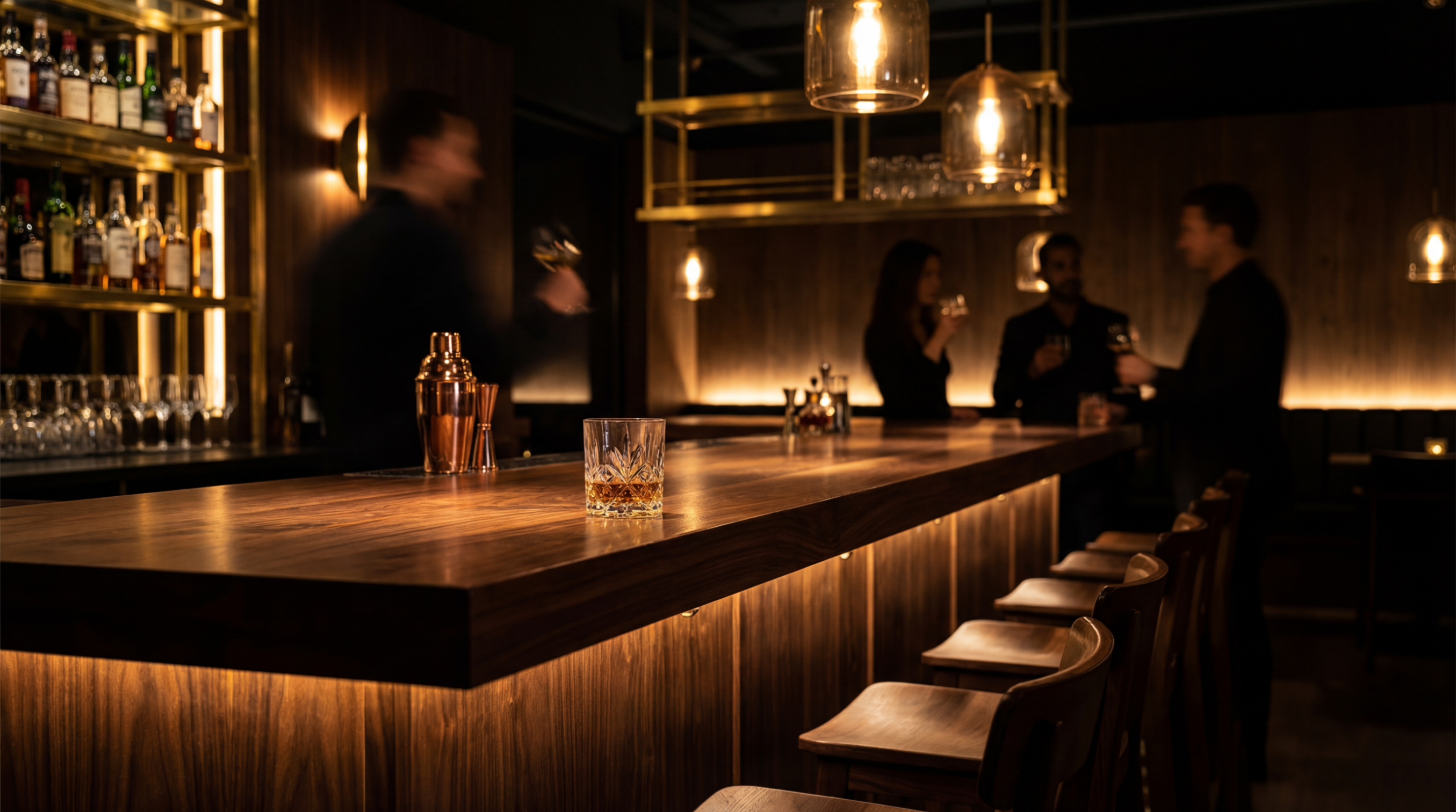 Upscale restaurant bar with walnut wood countertops, back bar shelving, and bar stools.